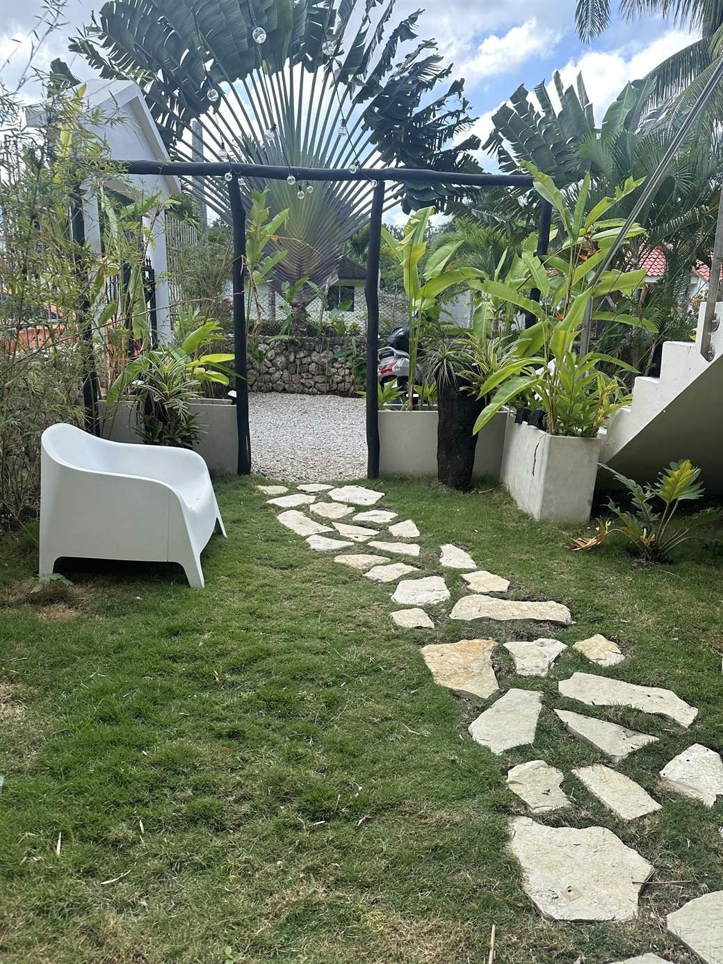 El Rincón de Abi: garden with a stone path, white outdoor furniture and plants